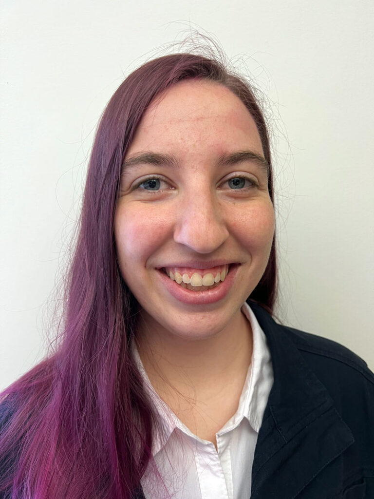 izzy bell (pictured in this headshot with long purple hair) will give the commencement address